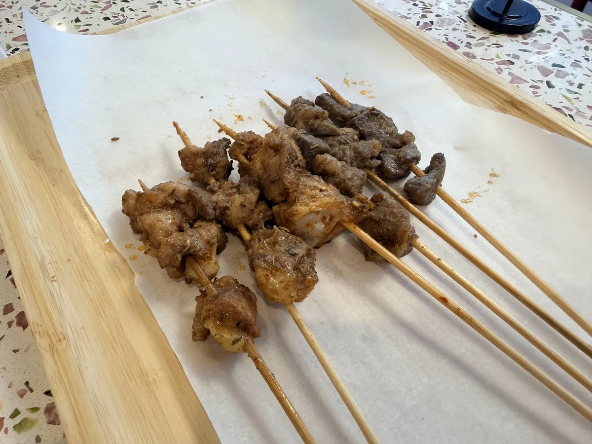 Assorted grilled skewers on a wooden tray